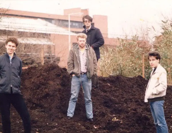 Promo photo of the 1980s British indie-pop outfit Soil: four young men stand on a very large mound of soil.